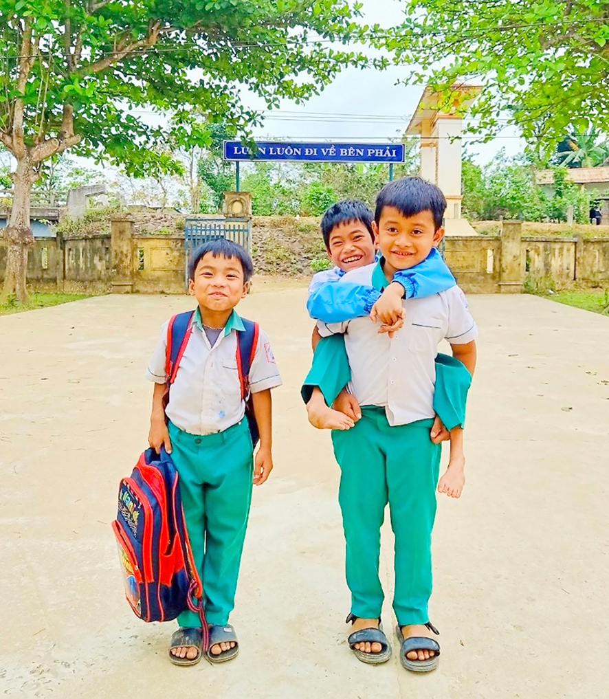 Hai học sinh thay nhau cõng bạn đến trường